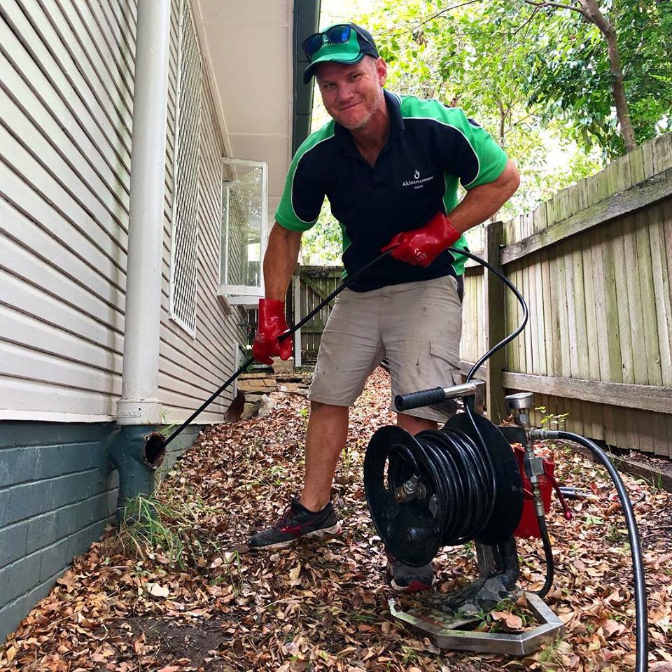Photo of Gavin Akins cleaning a drain | Featured image for Home Page for Akins Plumbing.