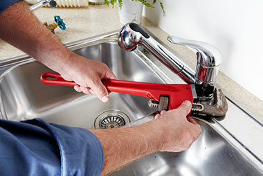 A person tightening a tap with a red wrench | Featured image for Home.