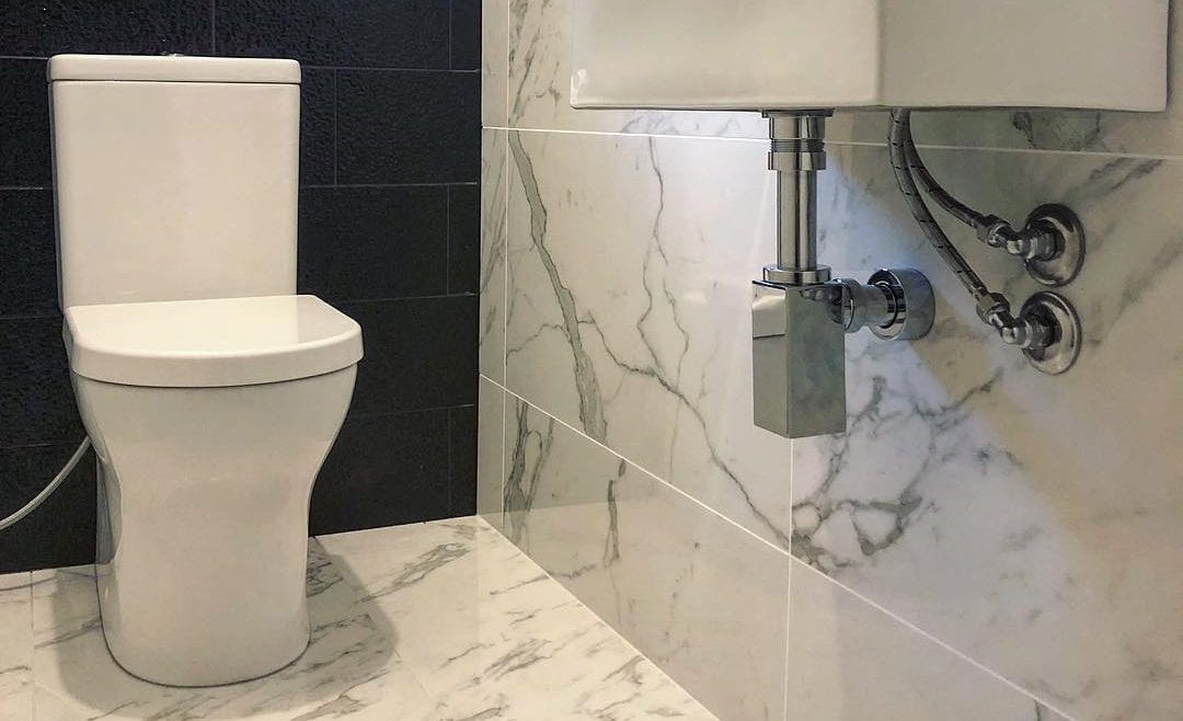 Image of a toilet in a marble bathroom | Featured Image for “how to unclog your toilet” | Blog