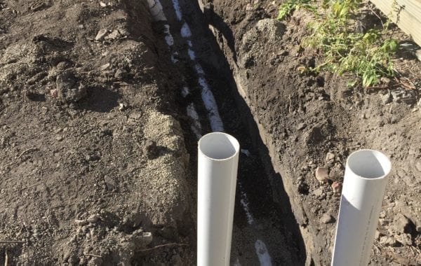 Drainage ditch and two PVC tubes sticking up in the ground | Featured image for Plumbing & Drainage Renovation Project Albion.