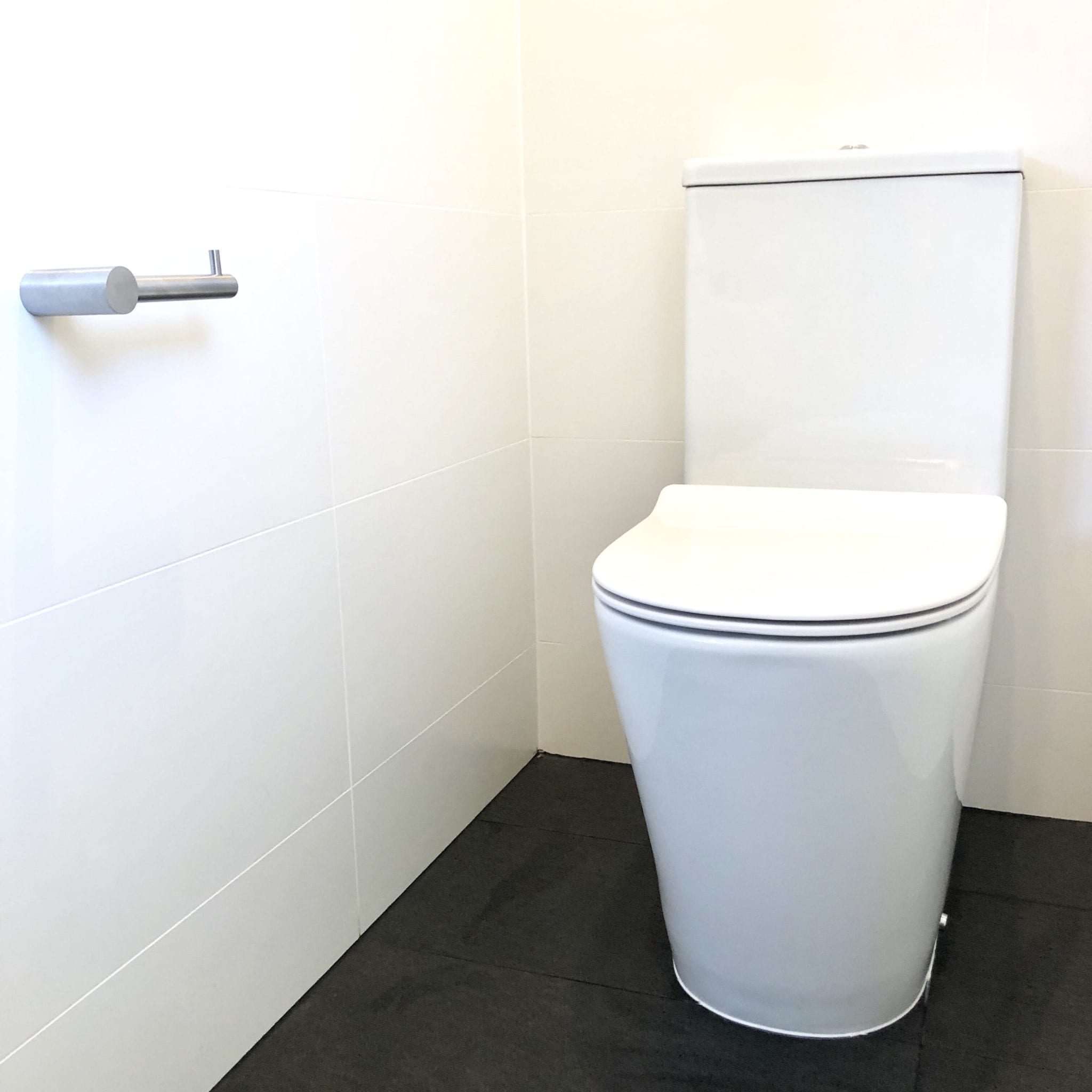A new white toilet installed in a modern bathroom. | Featured Image for the Signs of a Clogged Sewer Line Blog Article from Akins Plumbing.