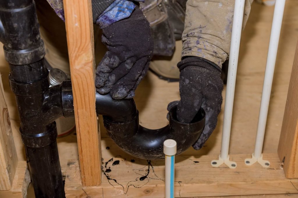 Plumber fixing drainage pipes | Featured image for Updating Plumbing: Know When to Upgrade Your Pipes blog for Akins Plumbing.