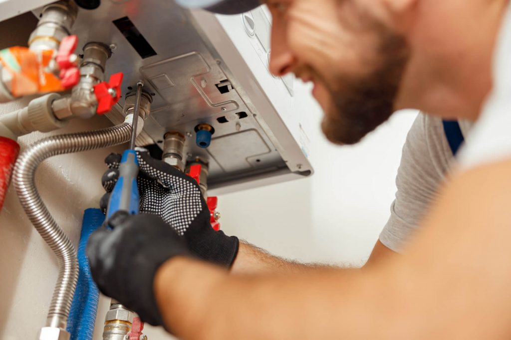 Closup of plumber conducting a water heater inspection | Featured image for Akins Plumbing Hot Water Heater Inspection service page.
