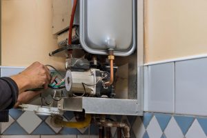Technician performing water heater maintenance | Featured image for Akins Plumbing Hot Water Heater Inspection service page.
